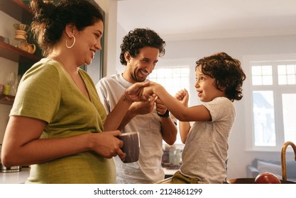 Happy Parents Spending Some Quality Time With Their Son At Home. Mom And Dad Playing With Their Young Son In The Morning. Young Family Of Three Smiling Happily In The Kitchen.