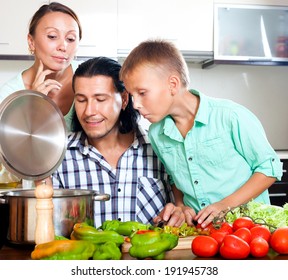 Happy Parents And Teenager Son Cooking Together At Home Kitchen