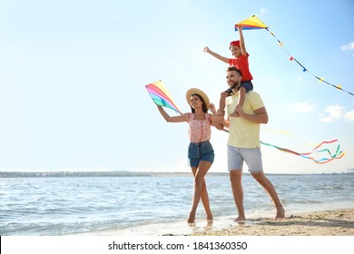 Happy parents and their child playing with kites on beach near sea. Spending time in nature - Powered by Shutterstock