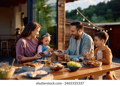 Happy parents and their kids eating donuts during family picnic day in their backyard.  - Powered by Shutterstock