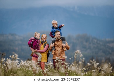 Happy parents with their little kids on piggyback at autumn walk. - Powered by Shutterstock