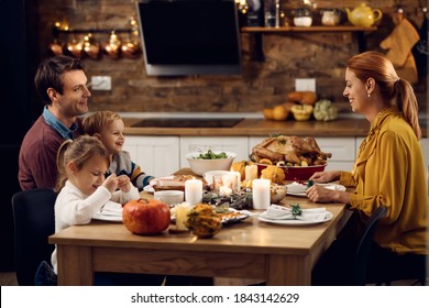 Happy Parents And Their Small Kids Having Thanksgiving Meal In Dining Room. 