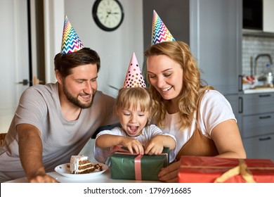 happy parents unpacking birthday gifts of their lovely daughter, congratulate and celebrate. at home in the kitchen, in party hats. family concept - Powered by Shutterstock