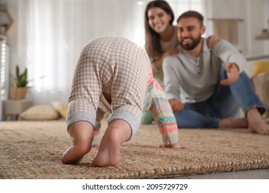 Happy parents watching their baby crawl on floor at home - Powered by Shutterstock