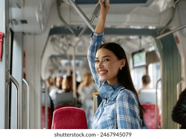 Happy passenger lady standing in modern tram enjoying comfortable ride in public transport indoors, riding by bus or trolleybus - Powered by Shutterstock