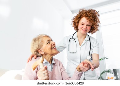 Happy Patient Is Holding Caregiver For A Hand While Spending Time Together. Elderly Woman In Nursing Home And Nurse. Aged Elegant Woman At Nursing Home