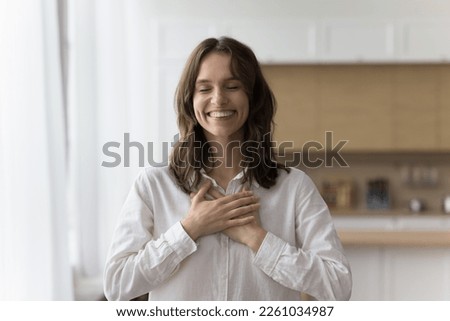 Happy peaceful pretty woman making gesture of gratitude, thank, pride, kindness, stacking hands on chest with toothy smile and closed eyes, enjoying peace, positive, thankful emotions