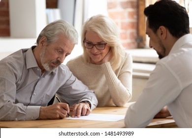 Happy pensioner couple sign contract with male realtor or broker buying house or property together, excited mature husband and wife put signature on document close deal with bank specialist