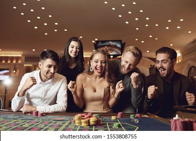 Happy people are betting in gambling at roulette poker in a casino - Powered by Shutterstock