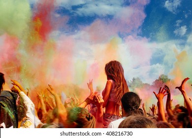 happy people crowd partying under colorful powder cloud at holi fest, festival of colors in summer, amazing moment