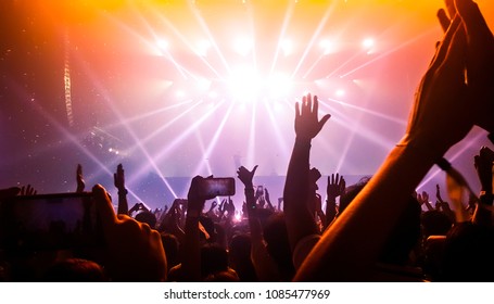 Happy people dance in nightclub party concert and listen to music from DJ on the stage in background. Cheerful crowd celebrate Christmas and New Year party 2018. Young people lifestyle and nightlife. - Shutterstock ID 1085477969