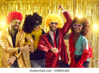 Happy people dancing gangnam style on stage with shiny golden background. Group of friends disguised in boas, glasses, sequin jackets and funny silly curly wigs having fun at night club disco party