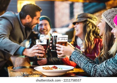 Happy people drinking beer at brewery bar out side - Beverage life style concept with guys and girls enjoying winter time together at open air restaurant patio - Warm filter with focus on glasses - Shutterstock ID 2211758557