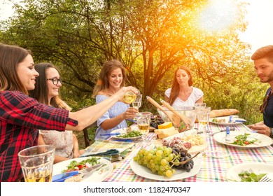 happy people enjoy their al fresco garden party in the late afternoon drinking wine and having some salad and a variation of cheese and salami sausages. there are four women and one man at the table. - Powered by Shutterstock