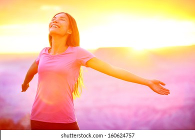 Happy people - free woman enjoying nature sunset. Freedom and serenity concept with female model in ecstatic enjoyment. Mixed race Asian Caucasian female model in 20 enjoying sunset, Grand Canyon, USA