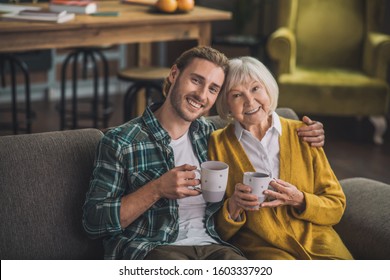 Happy people. Grey-haired elderly woman having tea with son