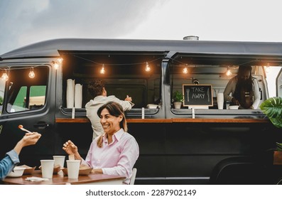 Happy people having fun eating and drinking outdoor at food truck restaurant - Focus on man head - Powered by Shutterstock