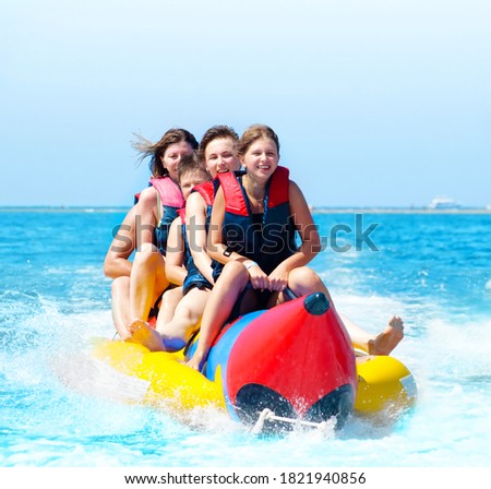 Happy people having fun on banana boat. Summer vacation
