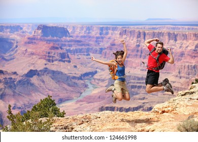 Happy people jumping in Grand Canyon. Young multiethnic couple on hiking travel. Grand Canyon, south rim, Arizona, USA.