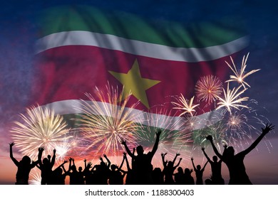 Happy People Are Looking Holiday Fireworks With Flag Of Suriname In Sky, Independence Day