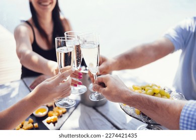 Happy people on the beach having a party, drinking and having a lot of fun in the sunset, they are wearing smart casual clothes and drink champagne