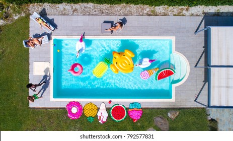 Happy People Partying In An Exclusive Swimming Pool With Animal And Fruit Shapes Mats, View From Above