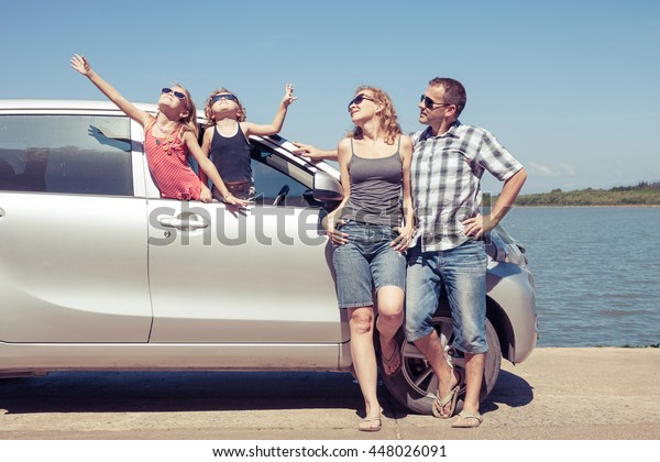 Happy people\
standing near car. They having fun on the nature.  Concept of\
friendly family and of summer\
vacation.