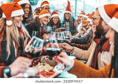 Happy people wearing santa claus hat having Christmas dinner party - Cheerful group of friends celebrating new year together - Winter holidays concept - Powered by Shutterstock