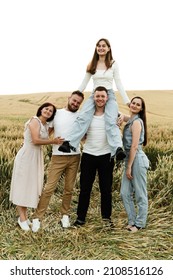 happy people in the wheat field have fun. people in the same style of clothing. family on a walk. family concept. father holding daughter on shoulders mother with son and daughter smiling