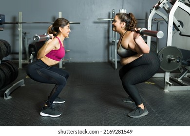 Happy Personal Trainer And Young Plus Size Woman Lifting Weights Together At The Gym 