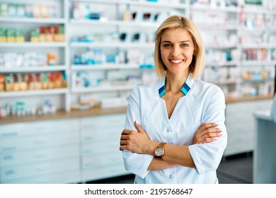 Happy pharmacist standing with her arms crossed in a pharmacy and looking at camera. - Powered by Shutterstock