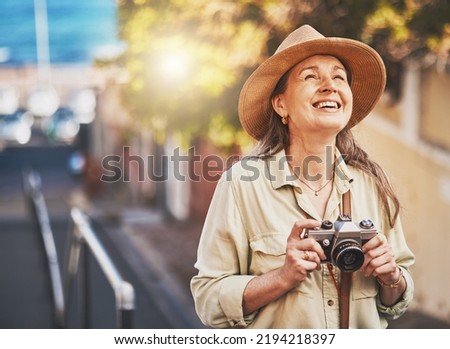 Happy photographer tourist taking photo of historic building with camera, smiling and carefree. Excited mature female solo travel journey, enjoying retirement while looking at bucket list