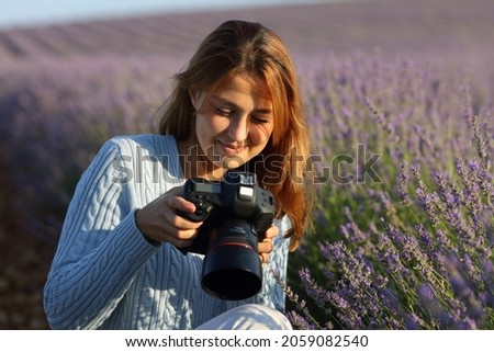 Happy photographer woman checking dslr camera in lavender field