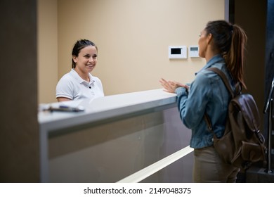 Happy Physical Therapist Communicating With Female Patient At Reception Desk At The Clinic. 