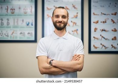 Happy Physical Therapist Standing With Arms Crossed At Clinic And Looking At Camera.