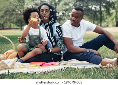 Happy picnic relax black people family with son blowing bubbles in garden - Powered by Shutterstock