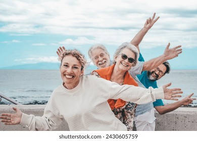 Happy playful multigenerational family group outdoors at seaside expressing joy by gesturing with hands towards camera - Powered by Shutterstock