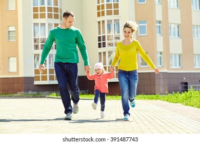 Happy Playing Family Outdoors. Young Parents With A Baby For A Walk In The Summer. Mom, Dad And Child