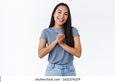 Happy, pleased charming asian woman clasp hands touched, receive help and thanking dearly, smiling joyfully, express gratitude and happiness, standing white background grateful - Powered by Shutterstock