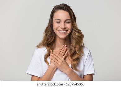 Happy pleased young woman thanking for care feel grateful holding hands on chest to heart isolated on white studio blank background, smiling sincere girl showing love heartfelt gratitude appreciation