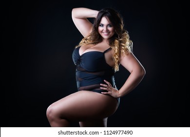 Happy plus size sexy model in swimsuit, fat woman with big natural breast on black studio background, overweight female body