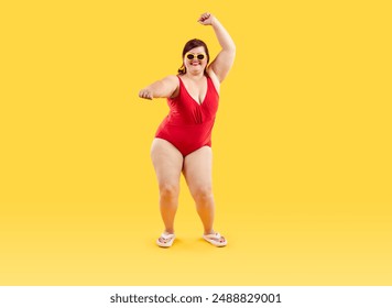 Happy plus size woman having fun at beach party on summer holiday. Full length studio portrait of cheerful confident smiling young fat lady wearing red one piece swimsuit dancing on yellow background - Powered by Shutterstock