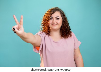 Happy Plus Size Woman. Peace Love. Body Positive. Healthcare Concept. Smiling Fatty Lady Showing Victory Sign Looking At Camera Isolated Blue.