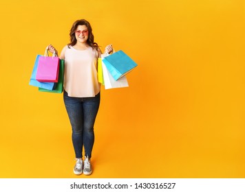 Happy Plus Size Woman With Shopping Bags On Color Background