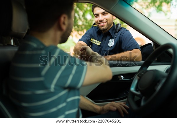 Happy police officer shaking hands and smiling\
to a driver after getting some\
help