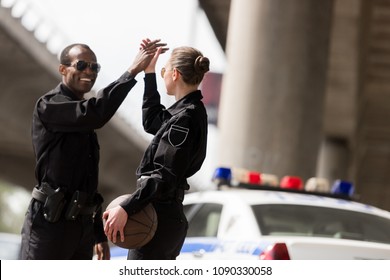 Happy Police Officers With Basketball Ball Giving High Five