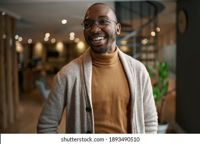 Happy portrait of african entrepreneur laughing and smiling. feeling excited and positive. Wearing trendy clothing and eye glasses in a modern working space - Shutterstock ID 1893490510