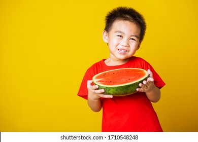 Happy Portrait Asian Child Or Kid Cute Little Boy Attractive Laugh Smile Wearing Red T-shirt Playing Holds Cut Half Watermelon, Studio Shot Isolated On Yellow Background