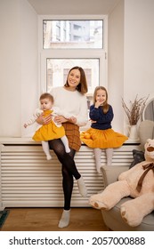 Happy Portrait Of Aunt With Her Little Nieces Sitting On The Window At Home