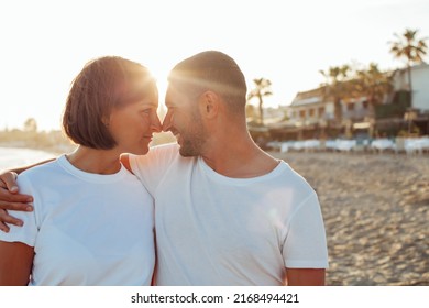 Happy Portrait Couple In Love On The Beach. Family. Diverse Couple On Summer Vacation. Portrait Beautiful Healthy Young Adults Girlfriend And Boyfriend Hugging Happy.